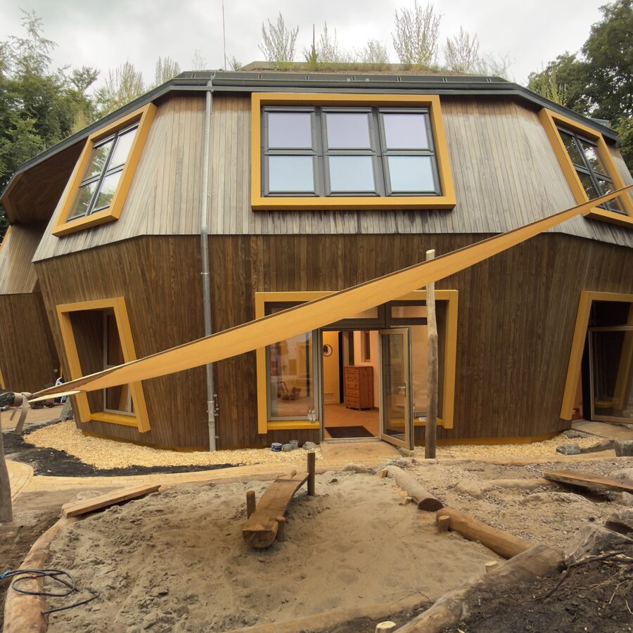 Neubau des Kindergartens mit Holzfassade, gelben Fensterrahmen und begrüntem Dach